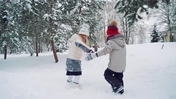 Children are Holding Each Others Hands in the Yard and Running Up in a Snowy Hill Together 
