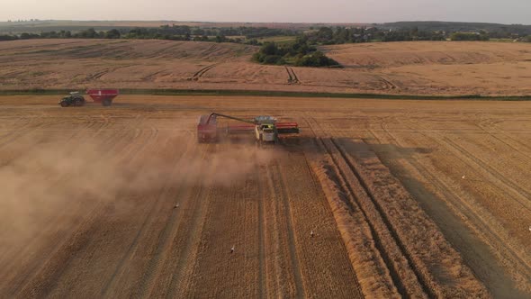 Aerial shot: combine pouring harvested wheat into tractor tipper