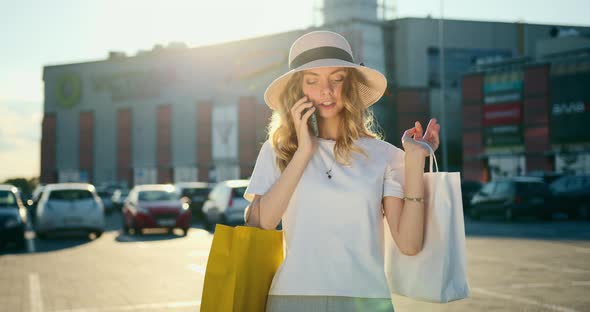 The Girl is Leaving the Shopping Center with Shopping Bags