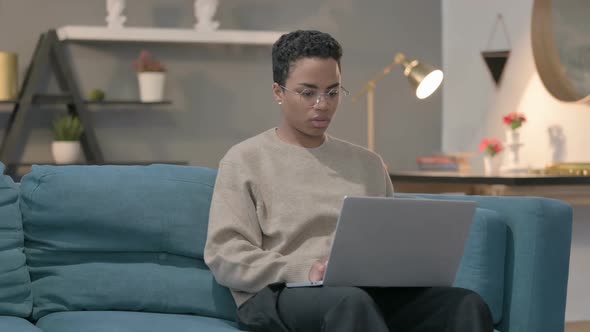 African Woman Working on Laptop on Sofa