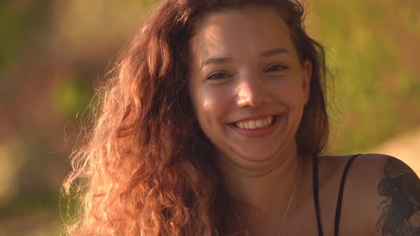 Happy Young Woman with Curly Hair and Crooked Tooth Ng and Showing Tongue