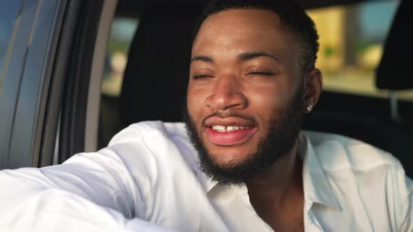 Headshot of Happy African American Handsome LGBTQ Man in Golden Sunset Light Sitting in Car Turning