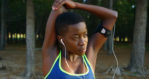 Female Athlete Performing Stretching Exercise While Listening Music in Forest 4k