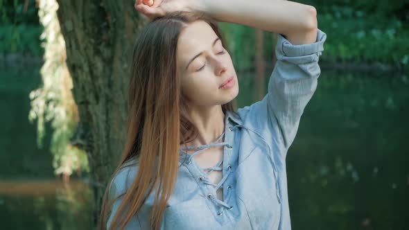 human and nature. beautiful young woman enjoying unity with nature sitting by a tree river