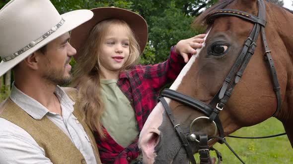 Cowboy and His Daughter Stroking a Horse