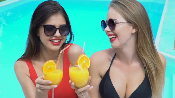 Beautiful Women Laughing, Celebrating and Drinking Cocktails Near Swimming Pool