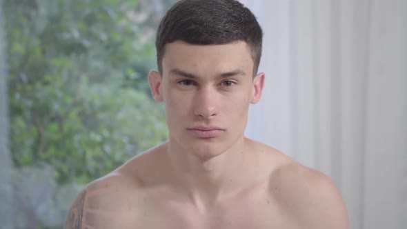 Close-up Portrait of Confident Handsome Caucasian Man Raising Head and Looking at Camera. Young