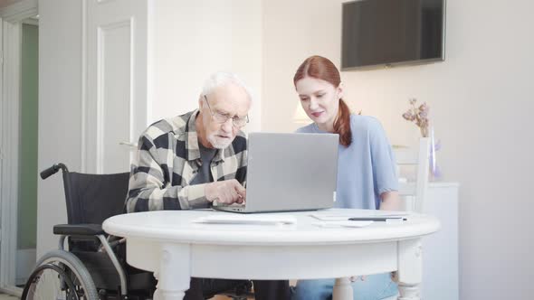 Grandfather Learns to Use Laptop While Granddaughter Helps Him