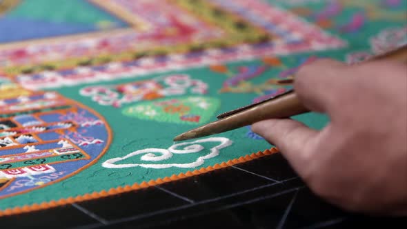 Tight shot of someone adding sand to a colorful sand mandala
