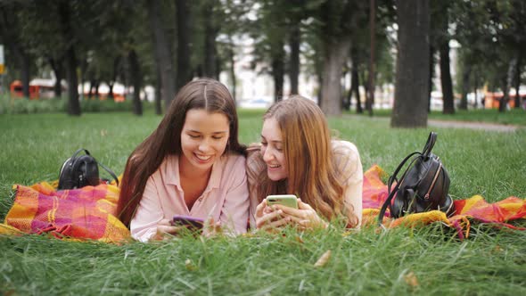 Students girls have a rest, use smartphone having fun on-line, chat with friends, watch funny video.