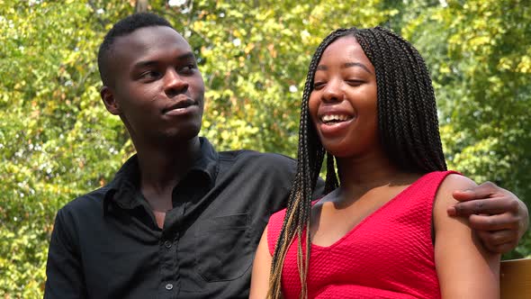 A Young Black Couple Sits on a Bench in a Park, the Man Talks and the Woman Listens