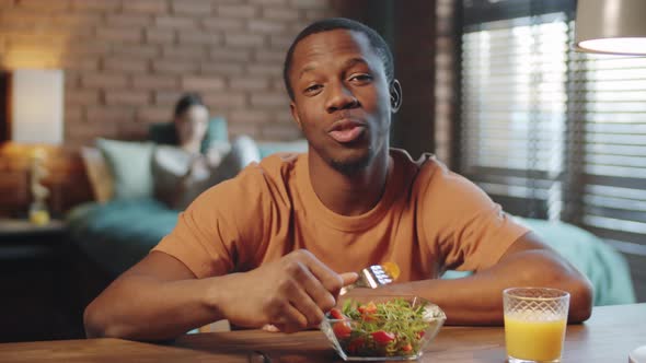 Black Man Eating Salad and Drinking Juice while Web Calling