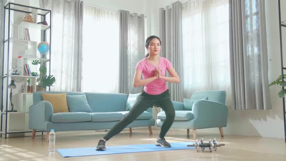 Asian Woman Exercising At Home, Stretching Her Legs