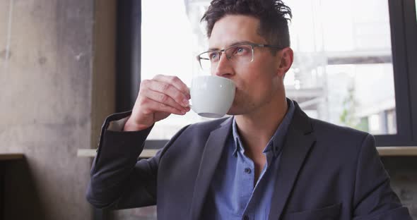 Caucasian businessman in thought, sitting at table drinking cup of coffee in cafe