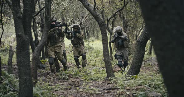 Squad of fully armed commando soldiers during combat in a forest scenery