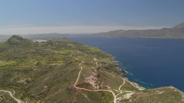 Backwards Aerial Pan of Cliffs Cascading into the Aegean Sea in Milos Cyclades