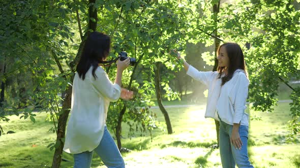 Pretty Girl Professional Photographer Wearing White Shirt Is Making Photos of a Girl in a Park on a