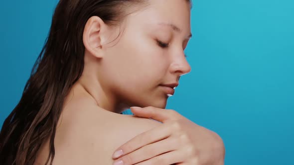 Fresh and Clean Girl Massaging with Arm Her Shoulder After Shower Isolated on Blue