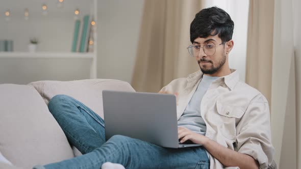 Young Guy Arab Freelancer Business Man Male Bearded Student in Glasses Lies on Couch at Home with