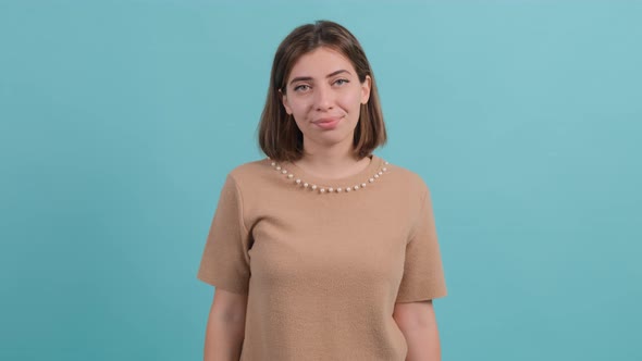 Happy Woman Showing Thumbs Down Gesture, Isolated Over a Turquoise Background.