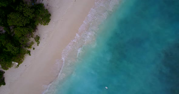 Wide angle overhead tourism shot of a sandy white paradise beach and aqua turquoise water background