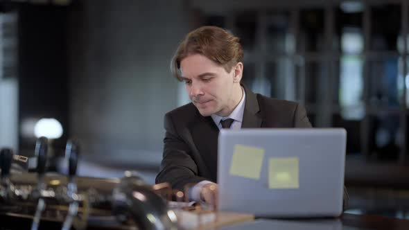 Focused Caucasian Man Checking Email Closing Laptop As African American Colleague Bringing Beer