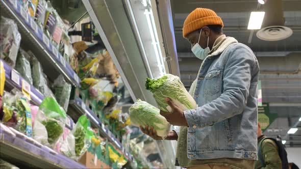 Black Guy Shopper Chooses Fresh Lettuce in Grocery Fridge