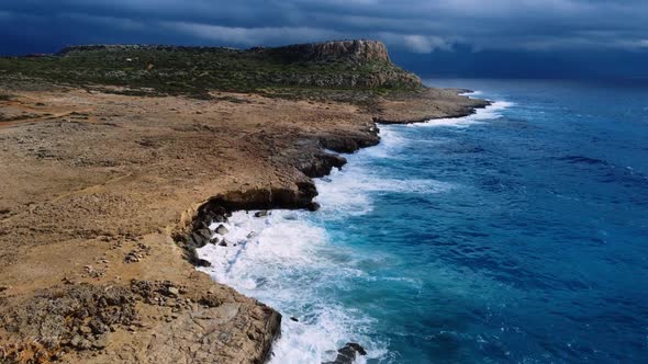 Sea Washes the Rocky Shore Above Aerial Shot Flying Over Coastline Cliffside with Blue Pure Water