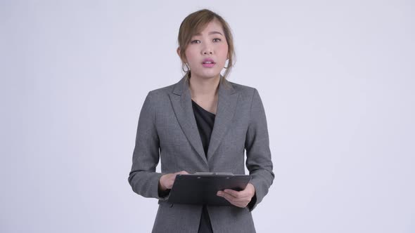 Young Happy Asian Businesswoman Bowing While Holding Clipboard