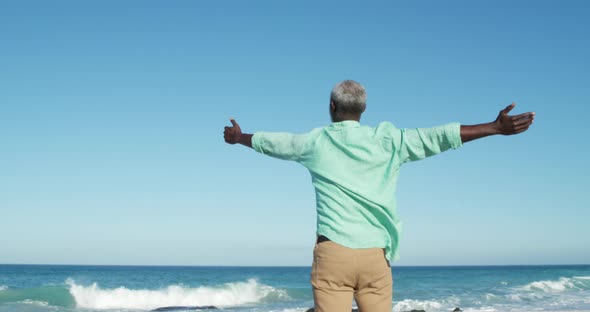 Senior man raising his arms at the beach