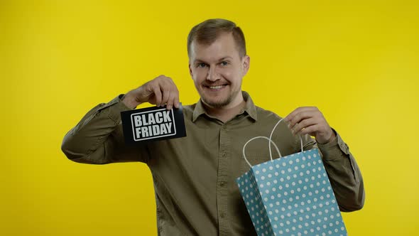 Attractive Man Showing Black Friday Inscription From Shopping Bag, Smiling, Rejoicing Discounts