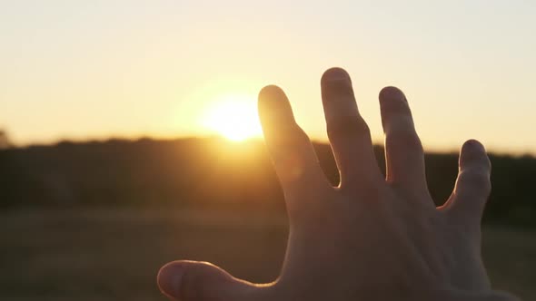 Male Hand Against Sunset. Touch the Sun. Sun Shines Through Fingers. Slow Motion