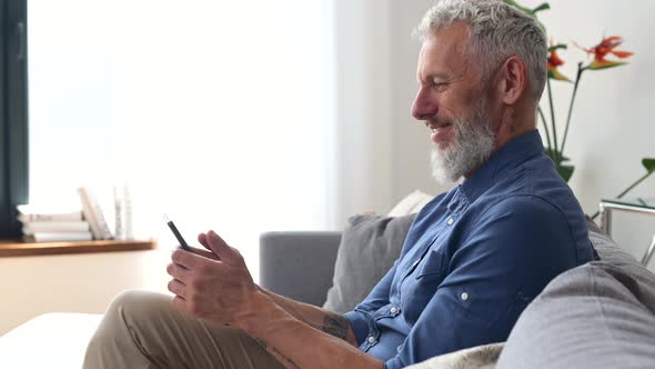 Greyhaired Middle Aged Hipster Man in Casual Shirt Using Smartphone