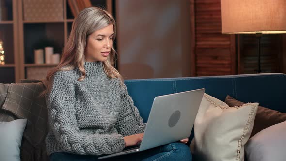 Freelancer Female Working Remotely Use Laptop at Evening Sitting on Couch Cosiness Home Interior