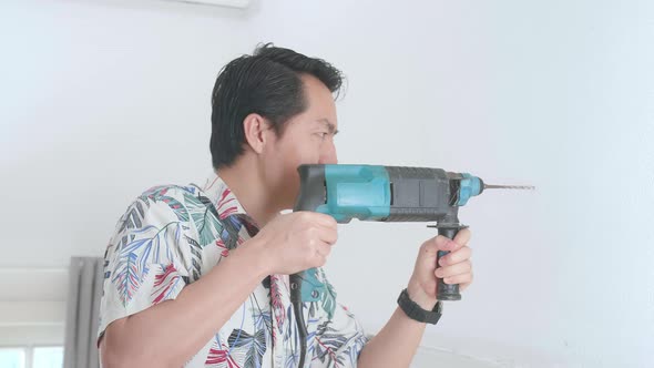 Asian Man Use Electric Drill On Wall In Him House, Home Improvement And Repairs