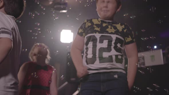 Kids Dancing and Bouncing Up & Down With Bubbles Floating Around, in Slow Motion - Ungraded
