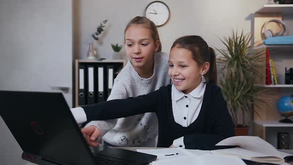 Two Happy Smiling Likable Teen Girls which Using Computer while Doing their Hometask