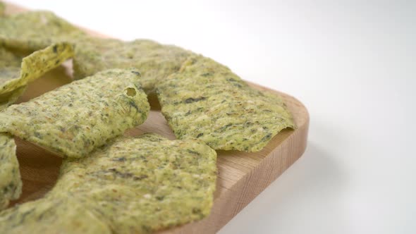 Herbal vegetable spinach bio crispy chips on a board on a white table
