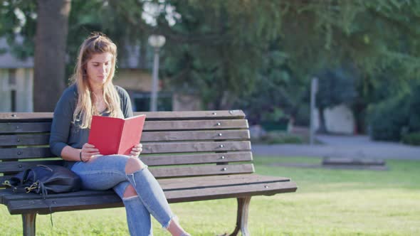 Young woman sitting on a bench, recieving a message and looking around