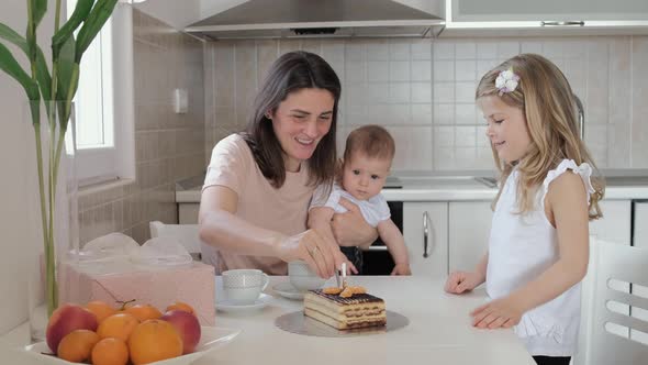 First birthday, mother lights a candle on the cake at home. Friends meet on a holiday with kids