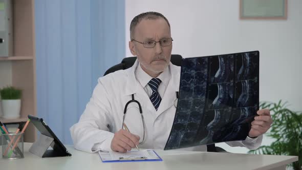 Spinal Surgeon Examining Backbone Mri, Making Notes in Patient's Medical Card