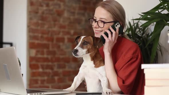 beautiful woman sitting at table with a dog and working in her home office