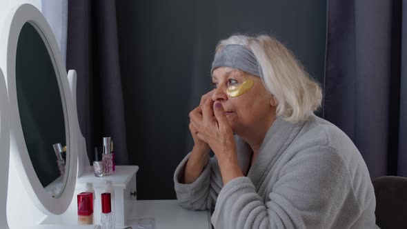 Old Senior Elderly Woman Grandmother Applying Anti-wrinkle Eye Patch, Putting Makeup on at Home