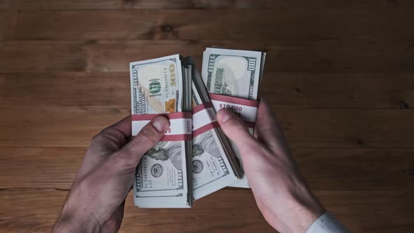 Male Hands Hold Three Stacks of 10000 US Dollar Bills and Show Thumb Up Sign