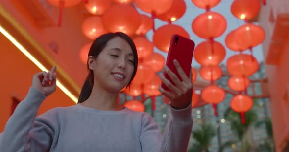 Woman take video on cellphone and speak to the phone with red lantern decoration