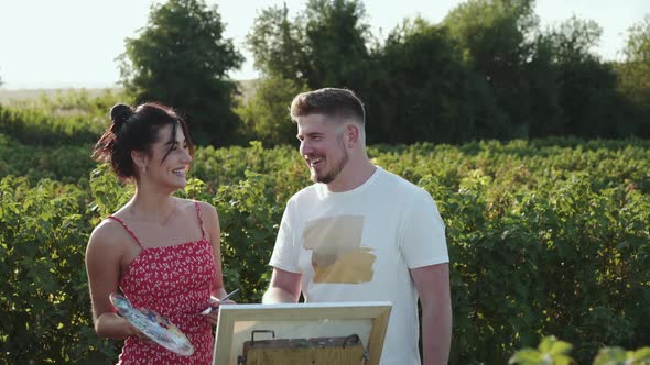 The Painter' Couple Rejoices and Talks with During Creativing on Canvas in Field