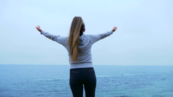 Mature Woman Is Praying On The Edge Of The Cliff Near Sea