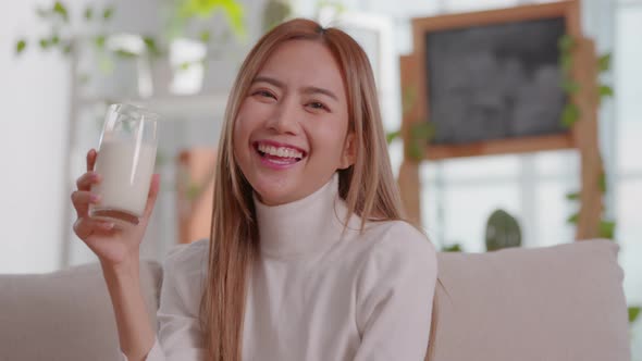 Healthy Young Asian woman Drinking milk with calcium for strong bone looking at camera