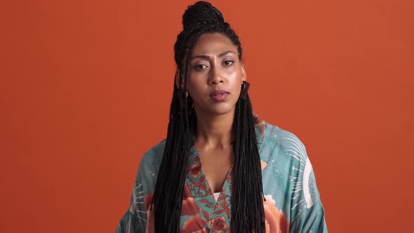 A confused african american woman pointing to her head with one finger