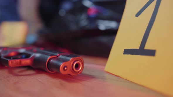 Close-up of Sign with Number One Standing Next To Gun Lying on the Floor. Evidence in Police Strobe alt